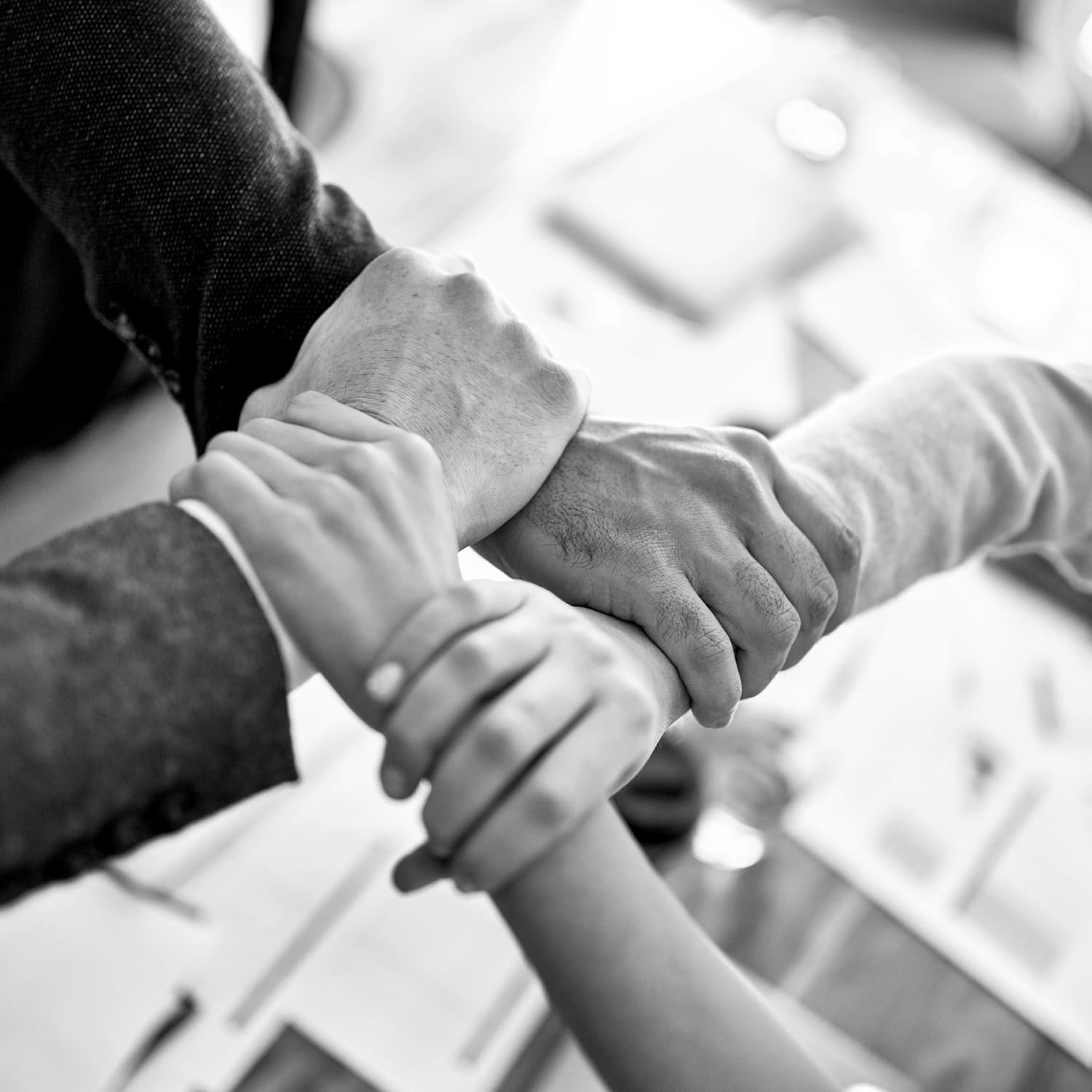 Team members' hands joined together over paperwork
