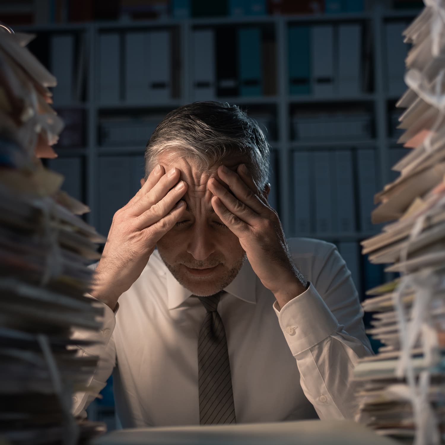 Stressed business owner surrounded by stacks of paperwork
