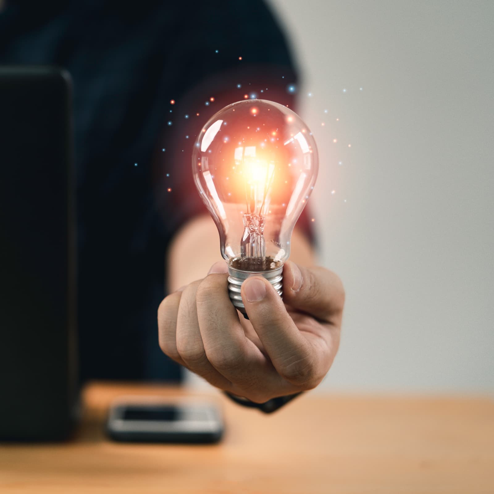 Hand holding a glowing lightbulb